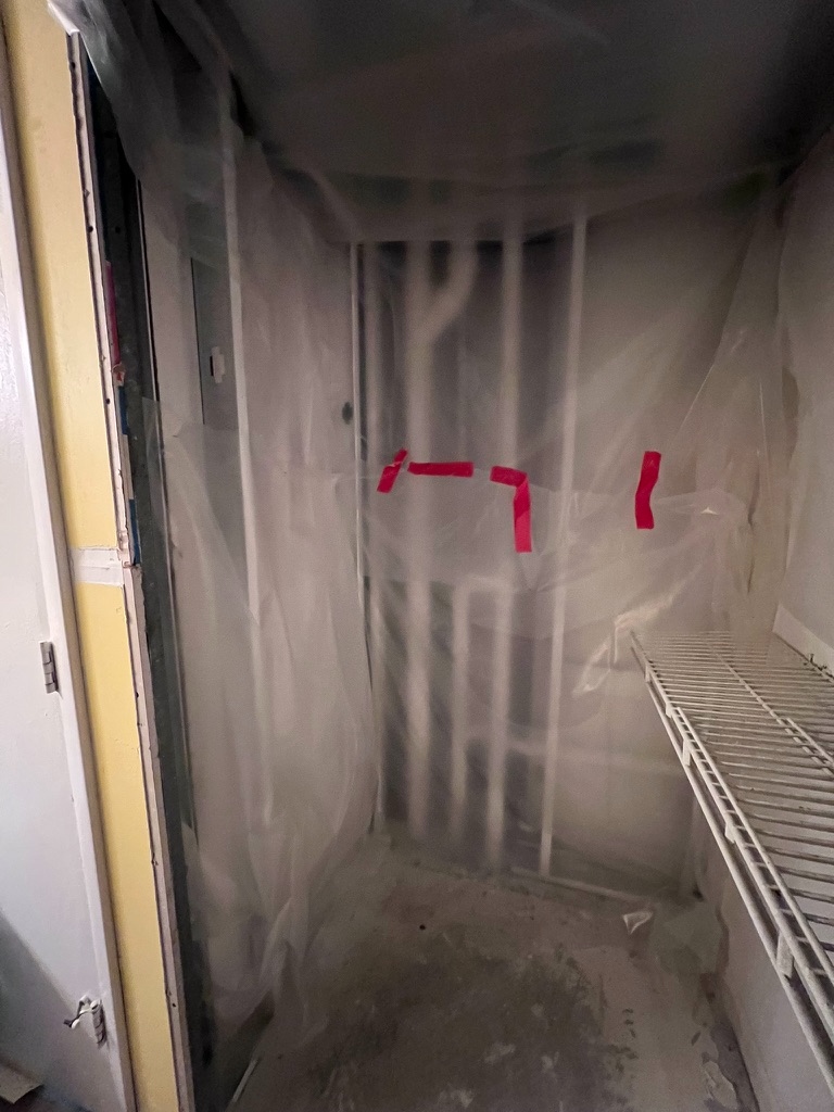 Interior containment barrier with poly sheeting and red tape at the entrance to the previously affected closet area