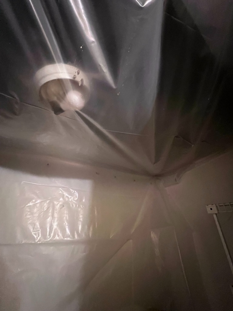 Ceiling containment sheeting near a light fixture inside the previously affected area