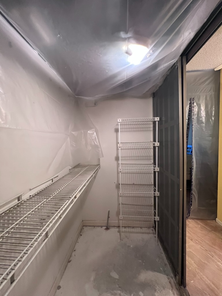 Ceiling staining above remediation containment sheeting inside a Coconut Creek condominium closet, evidence of remaining mold contamination after remediation work