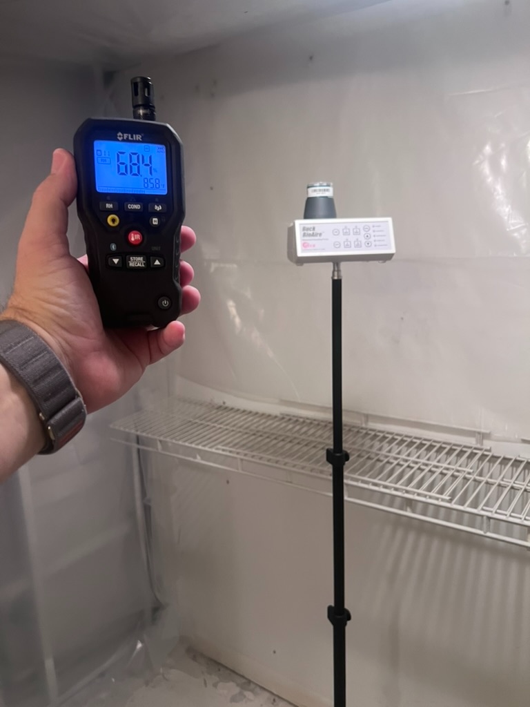 FLIR thermo-hygrometer reading 68.4 degrees Fahrenheit and 85.8 percent relative humidity inside the previously affected area, with a Buck BioAire air sampling pump running in the background