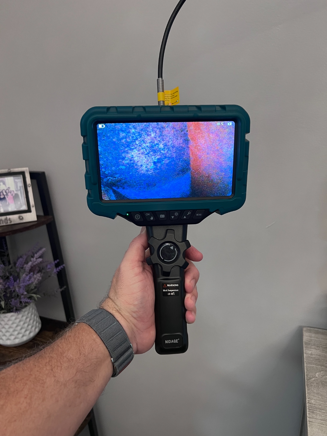 Inspector using a borescope to examine inside a wall cavity during a mold inspection