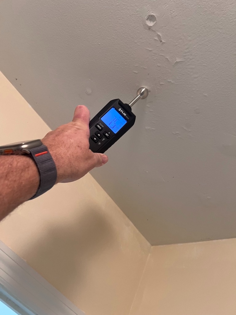 Inspector taking a ceiling moisture meter reading during a Home Enviro field inspection
