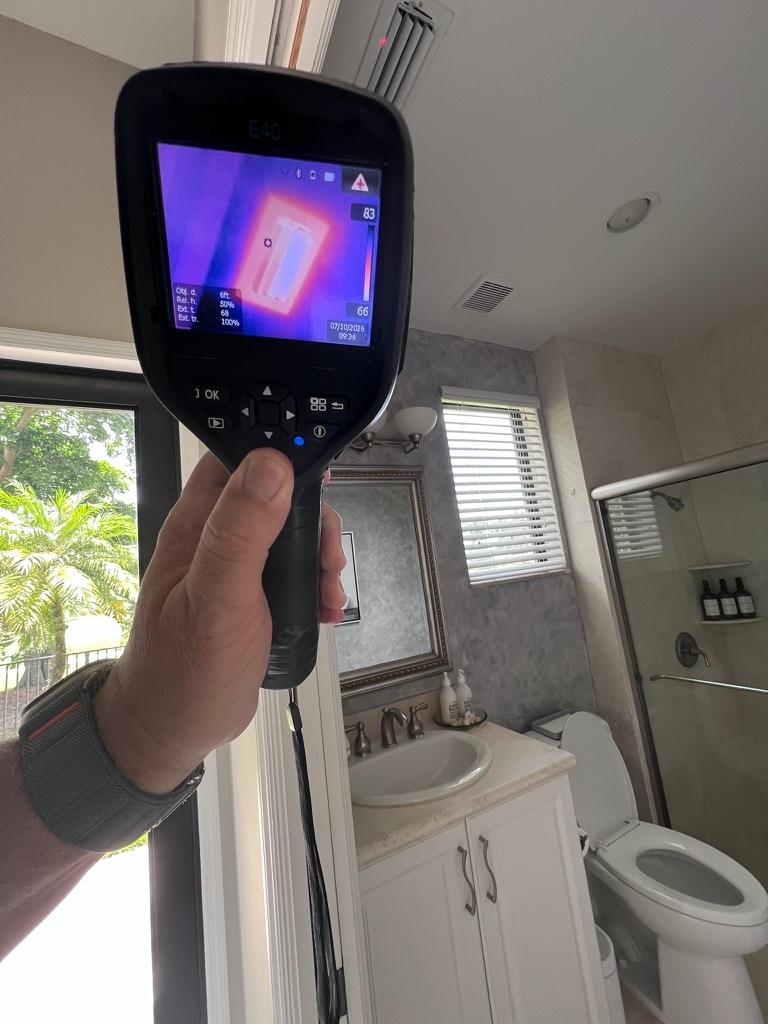 FLIR thermal imaging camera showing a temperature scan near a bathroom ceiling during an HVAC mold inspection
