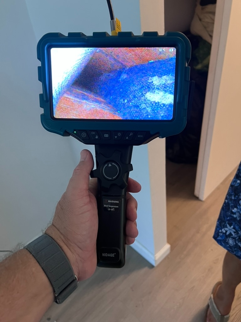 Borescope monitor displaying suspected microbial growth and moisture staining inside a concealed wall cavity